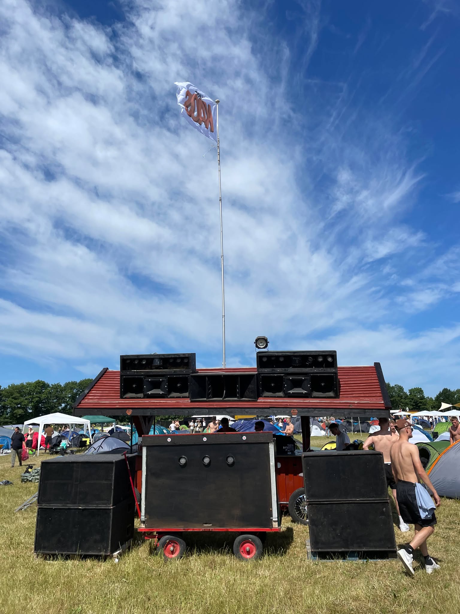 Camp Kaos' lydanlæg under blå himmel med flag på Roskilde Festival